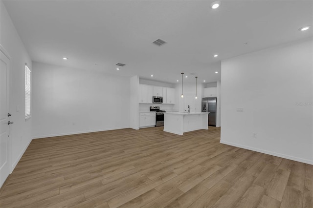 unfurnished living room featuring sink and light hardwood / wood-style flooring