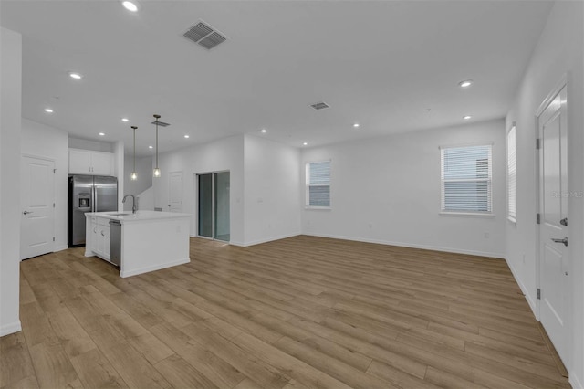 unfurnished living room with sink, light hardwood / wood-style flooring, and plenty of natural light