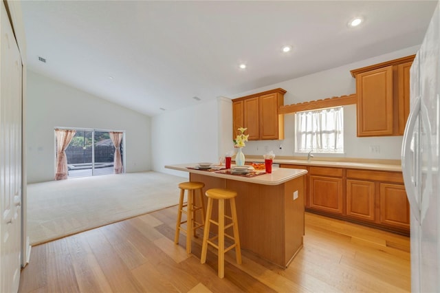 kitchen with light hardwood / wood-style floors, a healthy amount of sunlight, a center island, and vaulted ceiling