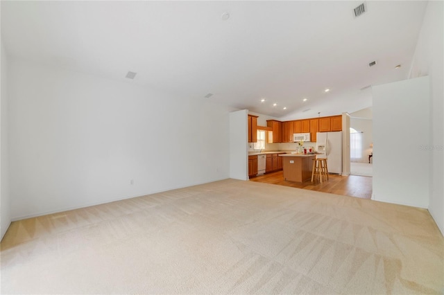 unfurnished living room featuring light colored carpet and vaulted ceiling