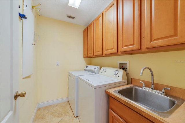 laundry area with a textured ceiling, light tile patterned floors, cabinets, sink, and washing machine and dryer