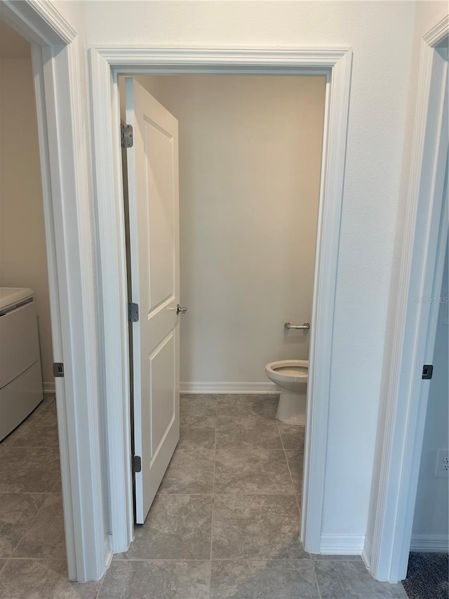 bathroom with toilet, tile patterned flooring, and washer / dryer