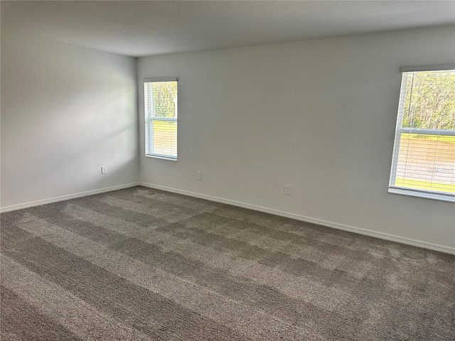 empty room with a healthy amount of sunlight and dark carpet