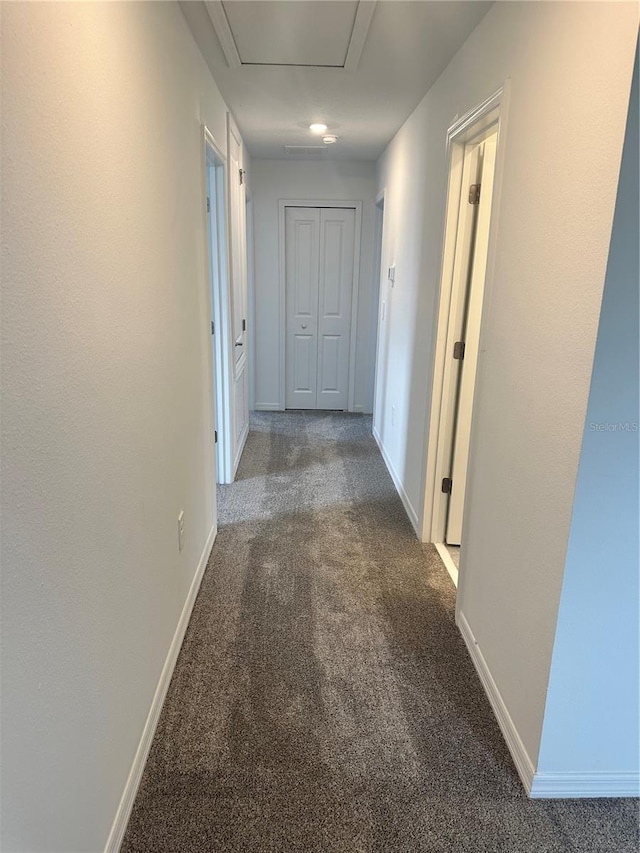 hall with dark colored carpet