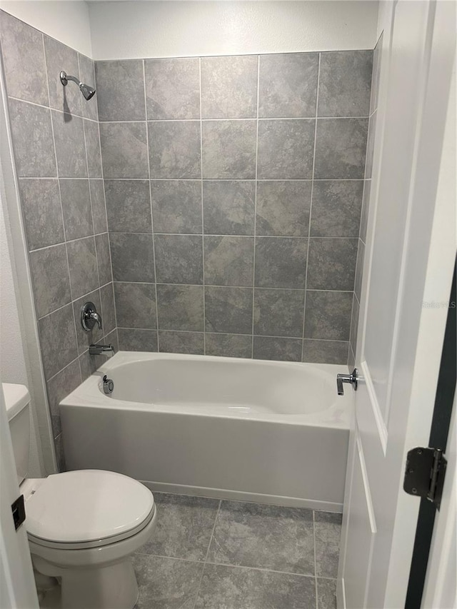 bathroom with tile patterned flooring, tiled shower / bath combo, and toilet