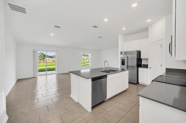 kitchen with stainless steel appliances, white cabinets, sink, light tile patterned floors, and an island with sink