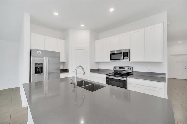 kitchen featuring stainless steel appliances, white cabinetry, sink, and a kitchen island with sink