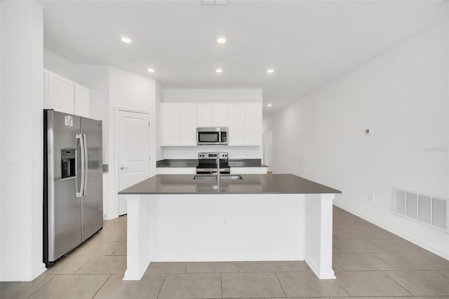 kitchen with stainless steel appliances, white cabinetry, light tile patterned floors, and a kitchen island with sink