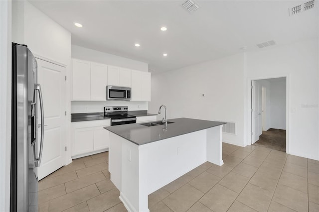 kitchen with light tile patterned flooring, white cabinetry, sink, appliances with stainless steel finishes, and an island with sink