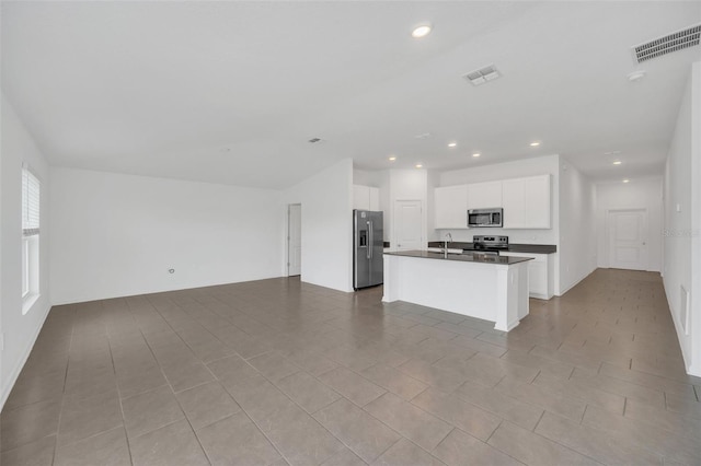 kitchen featuring a center island with sink, sink, appliances with stainless steel finishes, light tile patterned floors, and white cabinets