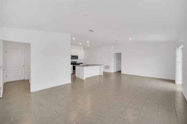 unfurnished living room featuring sink, light tile patterned floors, and vaulted ceiling