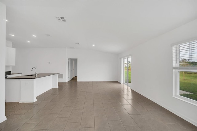 unfurnished living room featuring sink, vaulted ceiling, and a healthy amount of sunlight