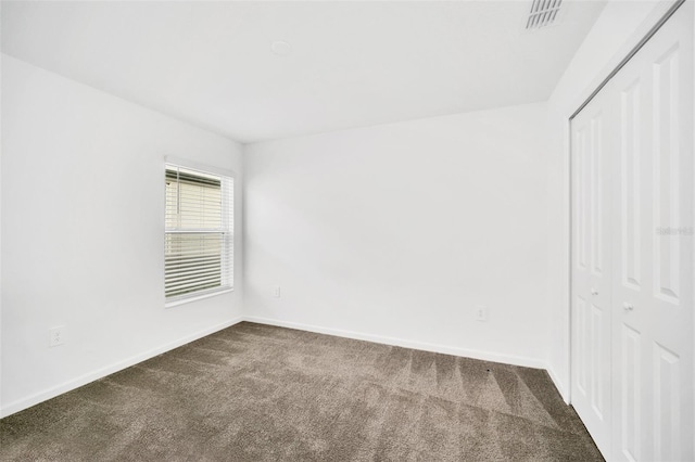 unfurnished bedroom with dark colored carpet and a closet