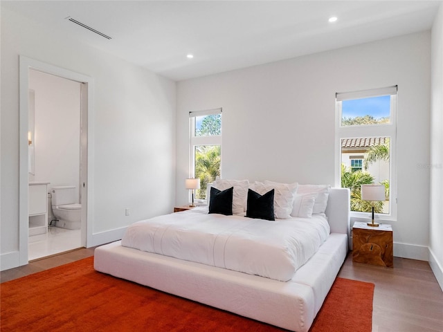 bedroom with ensuite bath and hardwood / wood-style flooring