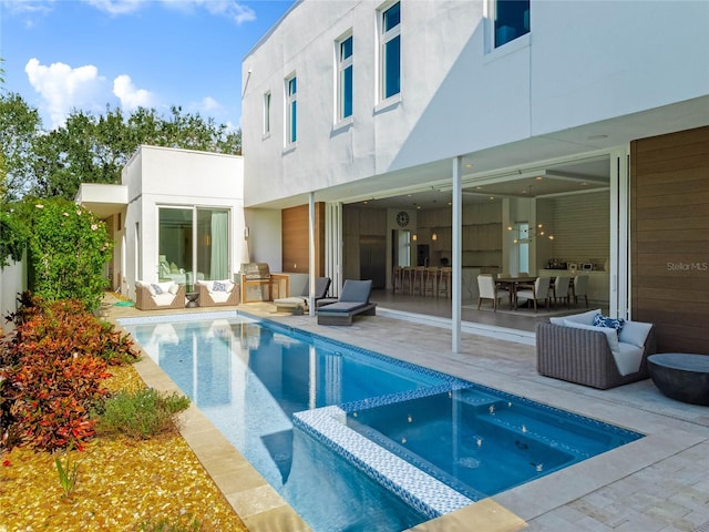 rear view of house featuring a patio area and a pool with hot tub