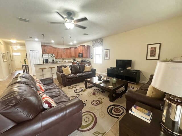 living room with ceiling fan and a textured ceiling