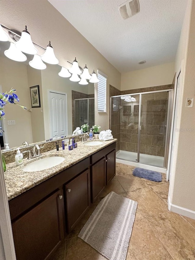 bathroom with tile patterned flooring, vanity, a textured ceiling, and walk in shower