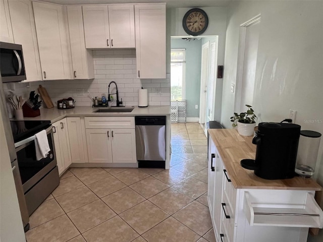 kitchen featuring white cabinetry, sink, appliances with stainless steel finishes, butcher block countertops, and decorative backsplash