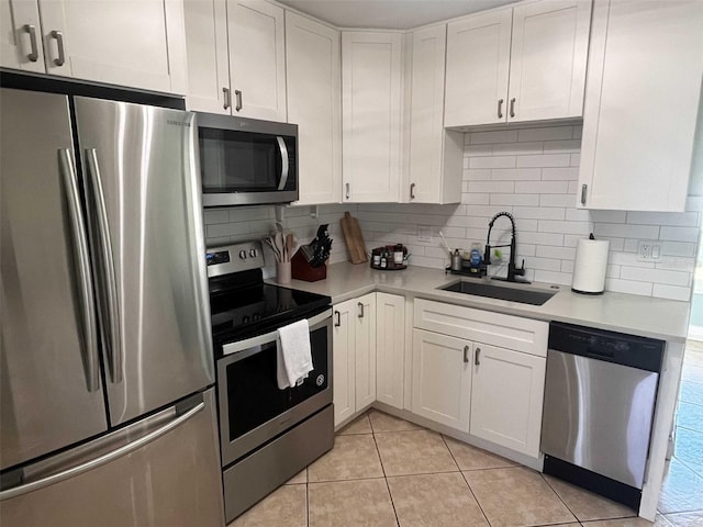 kitchen with sink, appliances with stainless steel finishes, light tile patterned floors, backsplash, and white cabinets