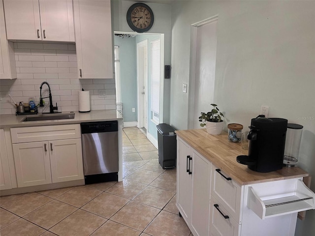 kitchen with white cabinetry, sink, light tile patterned floors, stainless steel dishwasher, and decorative backsplash