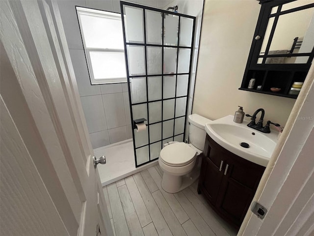 bathroom featuring tiled shower, vanity, and toilet