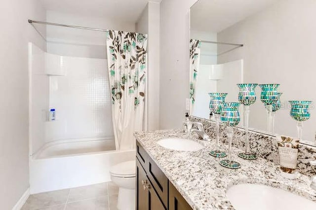 bathroom featuring double vanity, toilet, shower / bath combo, a sink, and tile patterned flooring