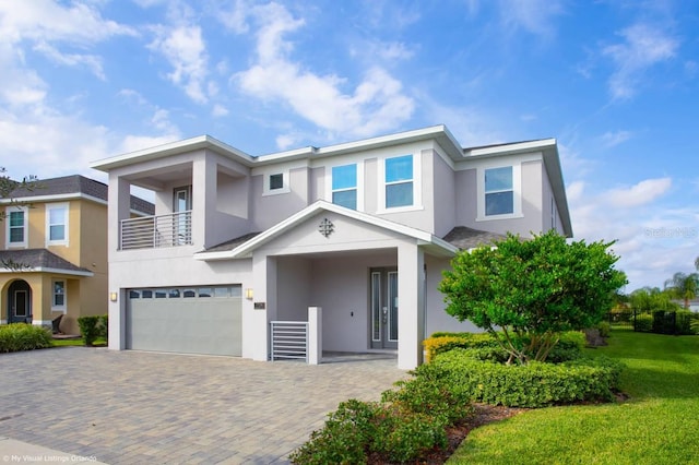 view of front facade with a balcony, a garage, and a front yard