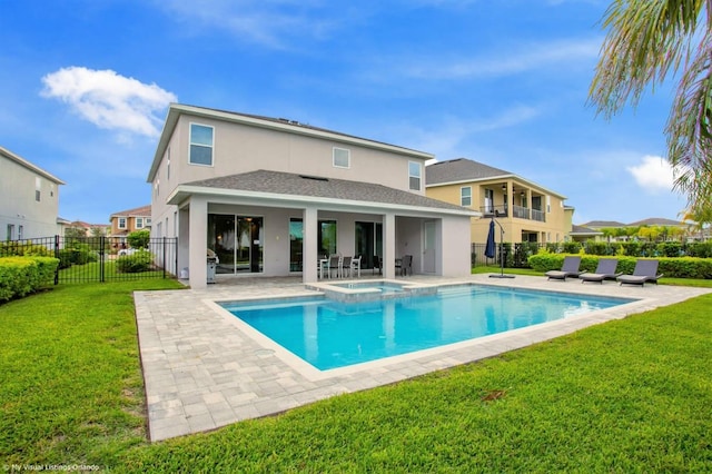 rear view of property with a lawn, a pool with hot tub, and a patio