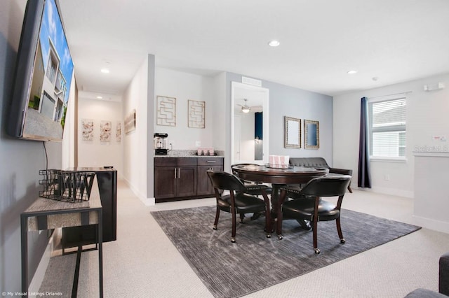 carpeted dining area with ceiling fan