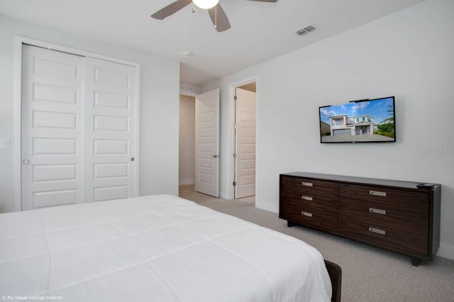 bedroom with light colored carpet, ceiling fan, and a closet