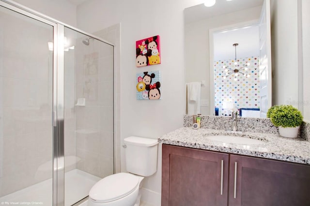 bathroom featuring toilet, vanity, a chandelier, and a shower with shower door