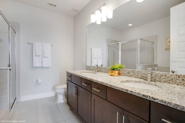 bathroom with toilet, vanity, tile patterned floors, and a shower with shower door