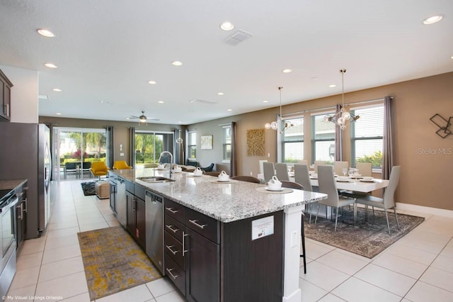 kitchen with sink, a breakfast bar, appliances with stainless steel finishes, a kitchen island with sink, and pendant lighting