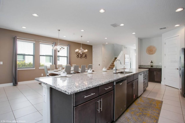 kitchen featuring appliances with stainless steel finishes, a notable chandelier, pendant lighting, sink, and an island with sink