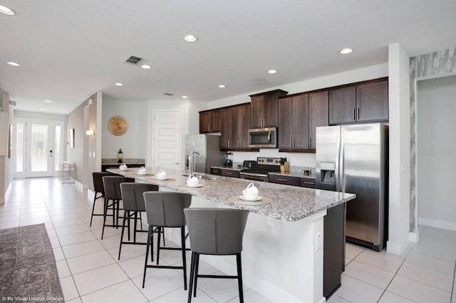 kitchen with a kitchen island with sink, appliances with stainless steel finishes, and a breakfast bar area