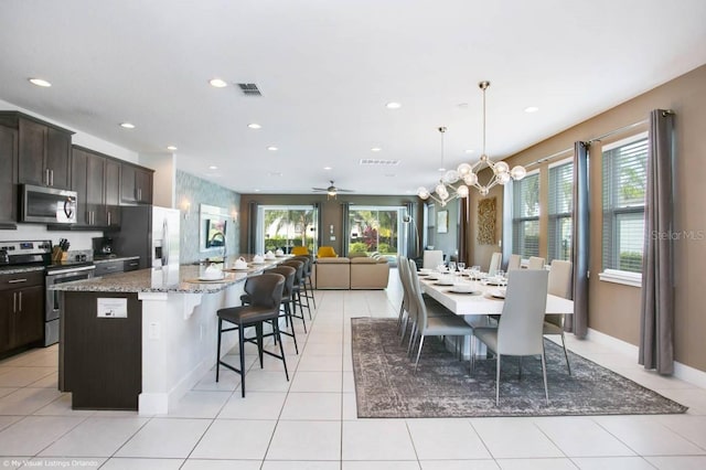 tiled dining area with ceiling fan with notable chandelier