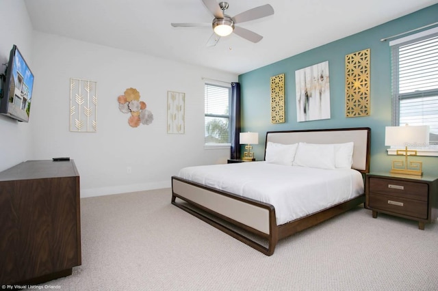 bedroom featuring multiple windows, light carpet, and ceiling fan