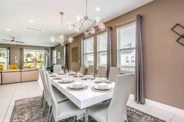 tiled dining room with ceiling fan with notable chandelier