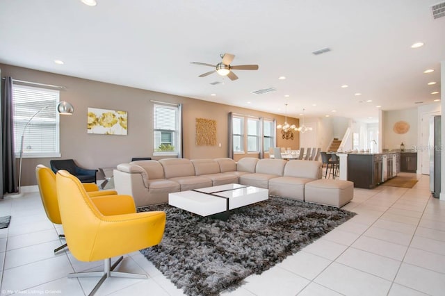 living room with ceiling fan with notable chandelier and light tile patterned floors