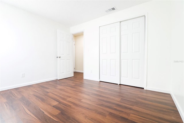 unfurnished bedroom featuring dark hardwood / wood-style flooring and a closet