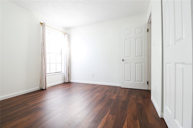 spare room with a textured ceiling and dark hardwood / wood-style flooring