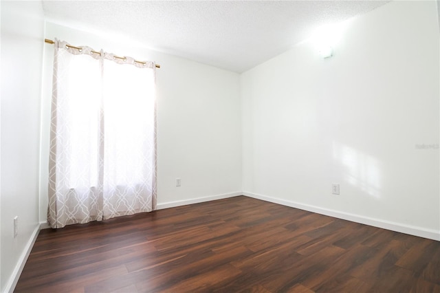 empty room with a textured ceiling and dark hardwood / wood-style floors