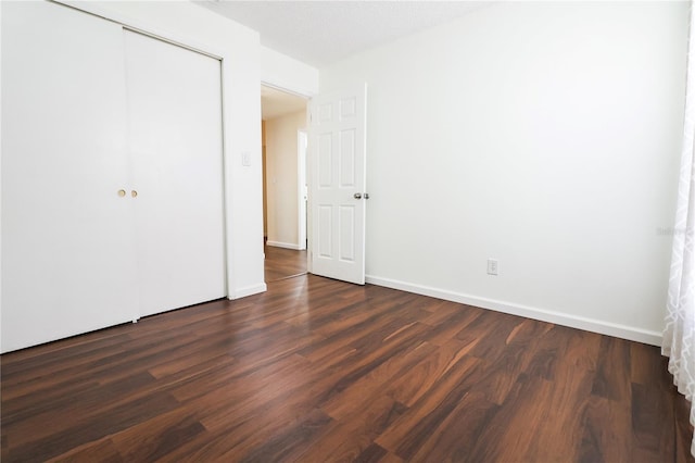 unfurnished bedroom featuring a closet and dark hardwood / wood-style floors