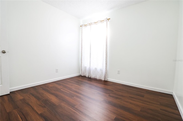 spare room featuring a textured ceiling and dark hardwood / wood-style flooring