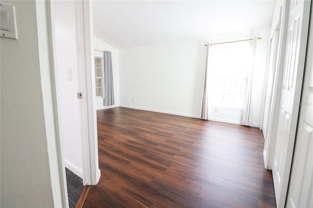 spare room with dark hardwood / wood-style flooring and vaulted ceiling