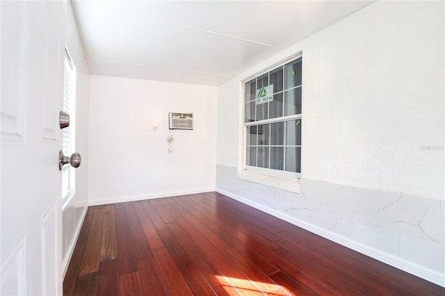 spare room with a wall unit AC and hardwood / wood-style floors