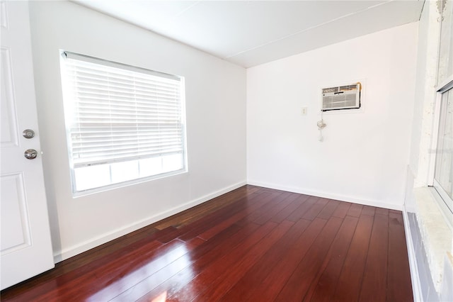 spare room with a wall mounted AC and dark hardwood / wood-style floors