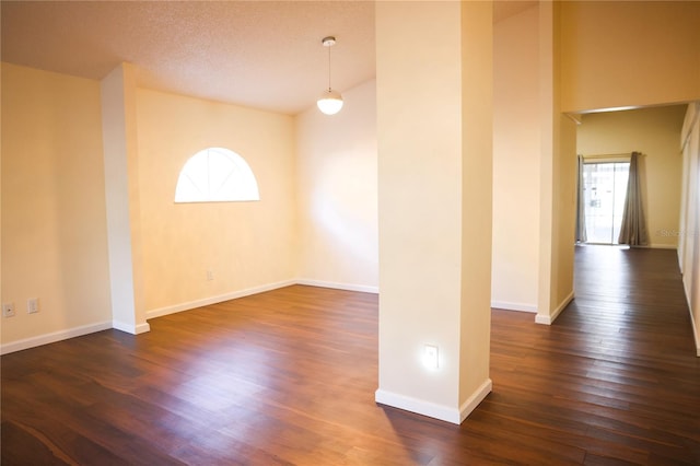 spare room with a textured ceiling and dark wood-type flooring