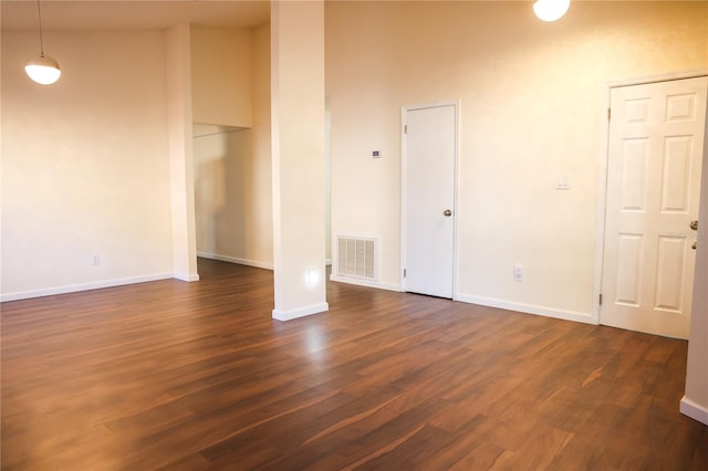 empty room featuring dark hardwood / wood-style floors and a towering ceiling