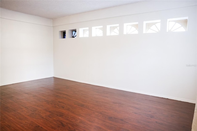 unfurnished room with dark wood-type flooring and a textured ceiling